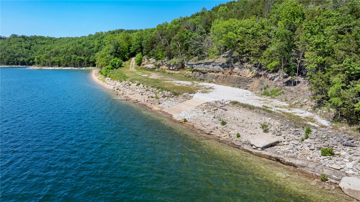 Discover Beaver Lake’s most remarkable private land offerings of 36.7 gated acres w/commanding lake views boasting a low corp line & direct water access, 2,400 ft of shoreline w/1,700 ft extending into the water at normal flood pool of 1,121 ft, private boat ramp, multiple building sites, community boat slip & essential infrastructure already in place. Designed for those seeking privacy, recreation & long-term legacy potential. Primary building site is perched above the water capturing stunning 180-degree panoramic views. Multiple additional building sites provide flexibility for future residences or expanded development. Gentle private drive leads to water’s edge of pristine shoreline. Also includes 1,000-gallon in-ground propane tank, underground electric, septic system, private well & 16’x32’ well house w/treatment system. A fifth wheel is currently staged on primary homesite fully connected to utilities. This one-of-a-kind property presents a rare opportunity to create a truly legacy-worthy Beaver Lake retreat.
