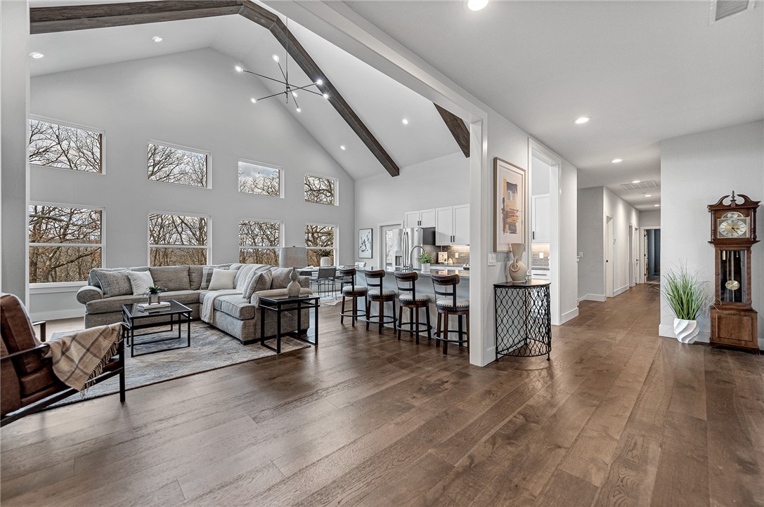 This LIKE-NEW, EXPANSIVE CUSTOM HOME offers exceptional privacy and picturesque views overlooking the Ozark mountainside. Upon entering this two-story home, you’re welcomed by soaring cathedral ceilings, abundant natural light, and open-concept living space. Designed with both relaxation and entertaining in mind, this home features multiple access points to a spacious covered back deck and patio, seamlessly connecting indoor and outdoor living. The walk-out basement provides a second living area complete with wet bar, bedroom, safe room, flex spaces ideal for home office or gym, and recreation room featuring a roll-up glass garage door. Additionally, there is an unfinished attic offering future potential for a media room or creative studio. Conveniently located just 15 minutes from the University of Arkansas and 20 minutes from the Fayetteville Downtown Square, this home delivers the perfect balance of tranquility and accessibility.