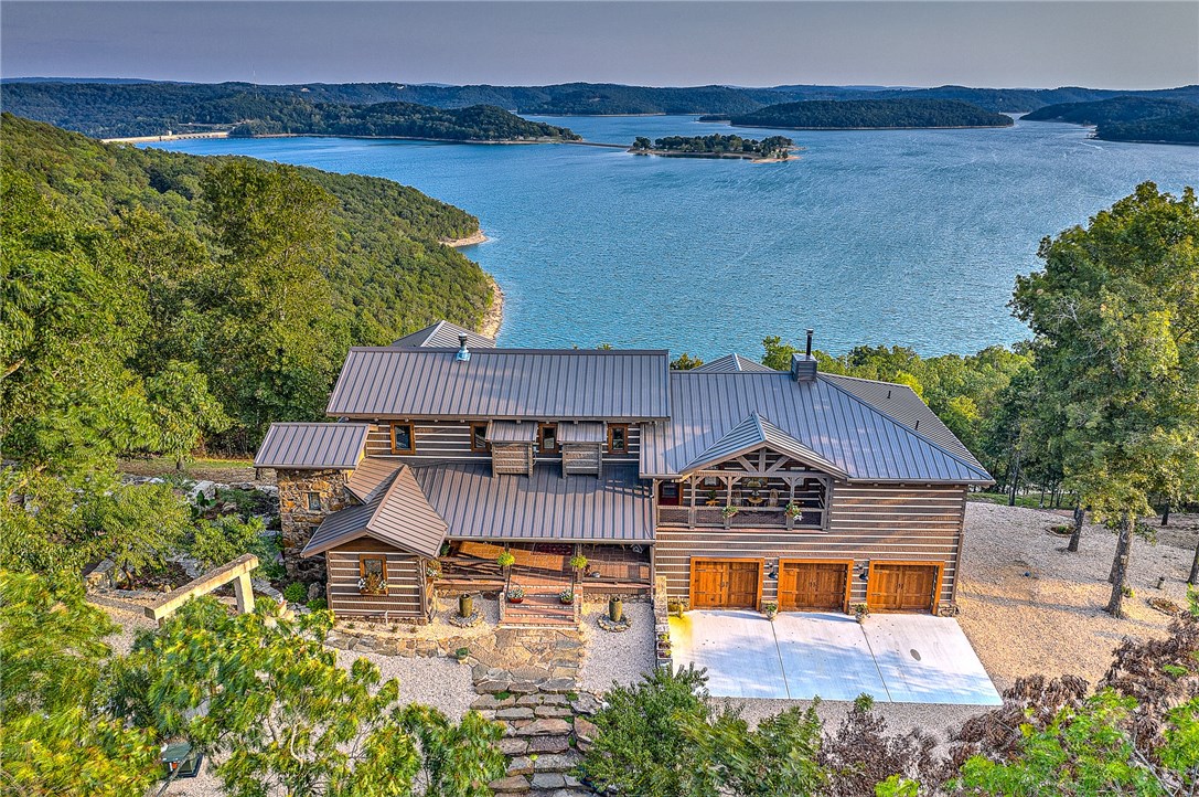 In the Ozarks; high up on a peaceful ridge of crystal quartz and stone, sits an amazing log and stone home, set apart from the rest of the world; Designed to be a sanctuary for birds, bees, and butterflies and Surrounded by perennial flower gardens; this home is like a jewel box which overlooks the North Shore of Beaver Lake and boasts some of the most breathtaking views in all of North West Arkansas.  This magnificent lake view Estate, known as Moon Stone Farm, is more than just a home; It's a functional ten acre self-sustaining sanctuary with various types of fruit and nut bearing trees, multiple vegetable gardens which grow abundant produce throughout the summer, a greenhouse which allows year-round optimal growing conditions, two separate dwellings, chicken house, roof mounted array of quality solar panels which offset the electric bill to a minimum, and so much more… Main home is made with high-end materials from the heavy, thick Hearthstone logs that create the walls to the strong metal roof. A Must See!