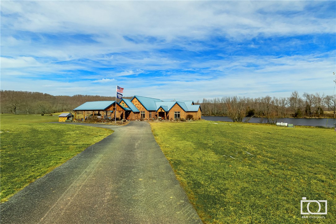 This 3800 square foot stamped concrete "log home" sits on 520 acres of fenced and cross fenced pasture for a working cattle farm of around 300 acres pasture and 100 head of cattle. House is a 3 br/2ba home with 10 inch concrete walls with radiant heated floors. Home overlooks one of the very large, stocked, and spring fed ponds on the property perfect for fishing off the dock or paddling kayaks or canoes.  Property has an additional 2000 square foot home for guests, a hunting bunk house, or ranch hands. Additionally property has a heated and cooled 50'X60' shop with sleeping quarters, kitchenette, bathroom and 12'X50' game room and bar, multiple hay barns, outbuildings, and a 40'X80' shop currently used for a classic car collection. Views for miles in all directions and very close to War Eagle Creek.   Large deer all over the property so perfect for hunting from one of the multiple deer blinds.