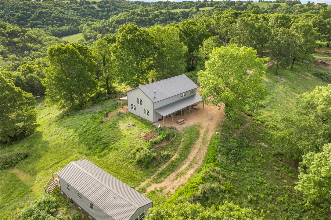 Set on 39.67 acres, this versatile property offers multi-generational living, income potential, or the perfect homestead setup. The main home, built in 2021, features 2,400 sq ft with 5 bedrooms and 2 baths, an open-concept living/kitchen area, LVP flooring, wood-burning stove, and a loft with additional bedrooms and flex space. Enjoy 500 sq ft of covered porches on the front and back. Two additional 768 sq ft homes each offer 2 bedrooms, 1 bath, open living/kitchen layouts, and private decks—ideal for guests or rentals. The land is set up for livestock with two fenced and cross-fenced pastures totaling over 10 acres, plus sheep and goat pens. Additional improvements include a 1,200 sq ft barn with stalls, greenhouse, chicken coops, and storage buildings. A 650-ft well services all homes and livestock. With a mix of open pasture and timber, this property is ready for your rural lifestyle or investment vision.