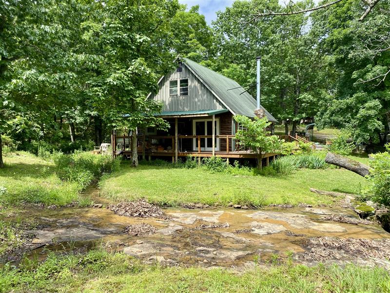 17.61 unrestricted acres in the Arkansas Ozarks featuring a 2 bedroom, 1 bath updated cabin, natural spring water system, 20 bed raised garden site, and room to create your own private homestead. Recent updates include newly refinished wood flooring, new cabinetry, and new windows in 2024, along with interior wood sourced directly from the property for a true handcrafted feel. The land offers established ATV trails lined with wild blackberries, raspberries, and dewberries, along with frequent sightings of whitetail deer and turkey. Two additional sites are already prepared for RV parking or a tiny home, providing flexibility for guests or future expansion. This property offers privacy, natural resources, and the freedom of unrestricted acreage, all in a peaceful Ozarks setting just a short drive to nearby towns, making it ideal for full-time living, a weekend retreat, or a long-term investment opportunity.