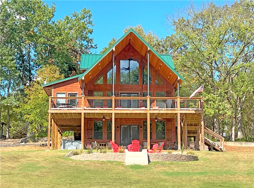 Peaceful refuge w/scenic views of the White River, one of the most beautiful retreats w/ river access between Beaver Lake & Table Rock. LAUNCH YOUR BOAT FROM THE RIVER FRONT ACCESS, FISH THE RIVER OR CRISE TO TABLE ROCK LAKE. This lodge combines rustic charm w/ modern comforts. Featuring cathedral wood ceilings, an open floor plan, a river rock fireplace, the signature red canoe lighting feature & a master bedroom ensuite. French doors lead to an expansive covered deck ideal for outdoor grilling with ample seating, overlooking the landscape and river.
Upstairs, a loft includes a custom entertainment nook, two uniquely furnished bedrooms w/ artisan-crafted reclaimed oak bunk beds, and a full bath. The walkout basement offers a bedroom, full bath, extra storage, a safe room, and a second living area, with access to an outdoor fire pit and saltwater hot tub. Near the river, enjoy an outdoor pavilion  w/a kitchenette, bath, and seating area, plus an additional secure space for vehicles and equipment. Ask 4 Updates PDF