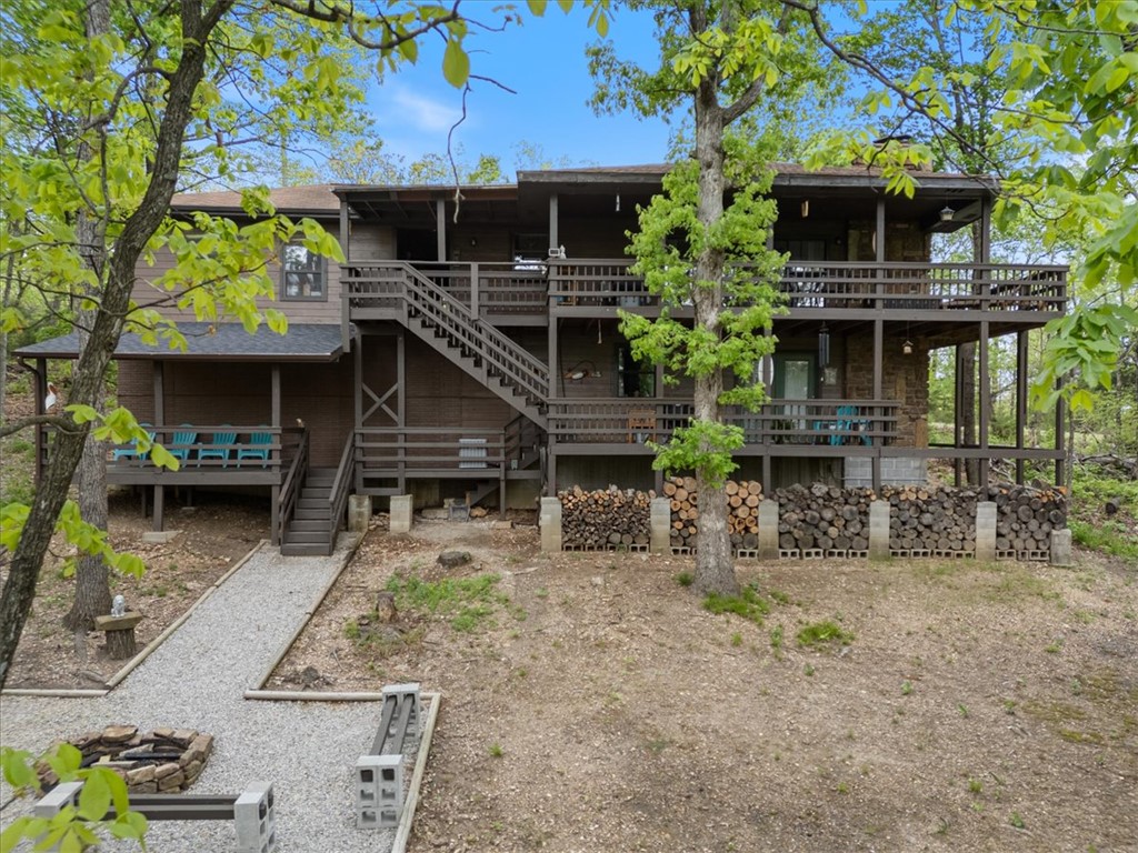 Ready for your new lake home? Holiday Island is the perfect community to enjoy both peace & quiet while having quick access to all the FUN like golfing, biking, swimming, kayaking, skiing & even hiking to local waterfalls. This home is the perfect investment with two completely separate units on each floor. Great for full time residence, multi-generational living, nightly rentals or part timers taking advantage of a huge Lake Home to entertain friends and family. Home has been renovated from top to bottom and is move in ready. BOTH floors have ALL the necessary comforts including large primary bedrooms with en suite baths, full kitchens, laundry rooms, large living rooms with natural stone fireplaces and expansive decks to enjoy the scenic view all year round. Complete with a  workshop out back (or a wonderful playhouse for the grands) a fire pit with bench seating for all to gather around. Be careful your peeps won't want to leave! Only 45 minutes from Branson & Bentonville and 20 min. to downtown Eureka Springs.
