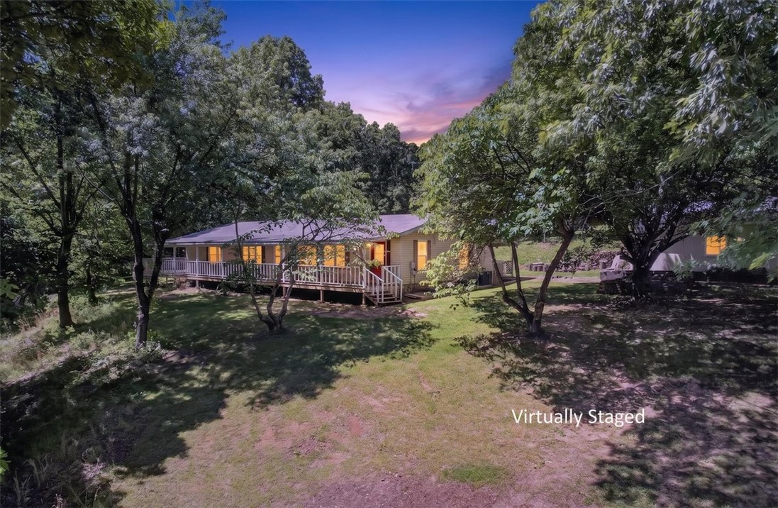 Peaceful country living with room to breathe. Situated on nearly 19 wooded acres, this property offers the privacy and quiet so many buyers are searching for while still being conveniently located just minutes from Hwy 412. The wraparound porch is truly the heart of the home, it's the perfect place to enjoy your morning coffee, unwind at the end of the day, and take in the sights and sounds of nature, and other wildlife frequently passing through the property. Around the home, you’ll find several great flat, usable areas ideal for gatherings, campfires, outdoor activities, gardening, or simply enjoying the space and freedom that comes with country living. Sellers have spent considerable time cleaning up and improving the land around the home and will also leave a generous supply of firewood ready to use. The property includes a detached 24x30 two-car shop, along with an additional storage shed added by the current owners that will also convey.