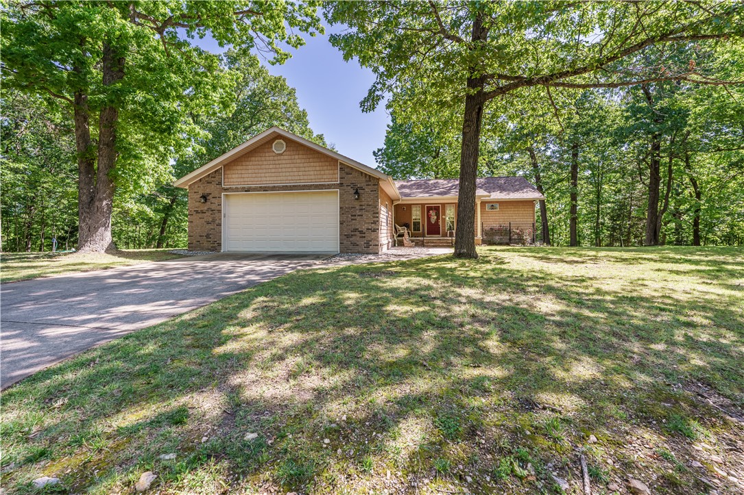 Warmth & Charm await you in this Beaver lake area get-a-way. The property is 3 lots, totaling 4.47acres with seasonal lake views. The views could possibly be year-round with some selective tree clearing. The home is 2 bedrooms, 2 baths, laundry & large open floorplan with kitchen, dinning & living room leading to a large deck on the rear. It was built with handicapped access in mind with extra wide hallway, wide doors, grab bars in primary bath as well as a ramp to enter from garage (which is removeable). The property also has a parking area for an RV with 50amp electric, water and septic hook up as well as an attached 2 car garage with work bench area. All of this on a nice level area with front yard. The lot to the left of the home has a large level area & could be used to build a guest house or shop building for extra toy storage. All this just a 5 min drive to Starkey Marina or Beaver Lake Dam/White River & about 20 mins from historic downtown Eureka Springs. Schedule your private showing before it's gone.