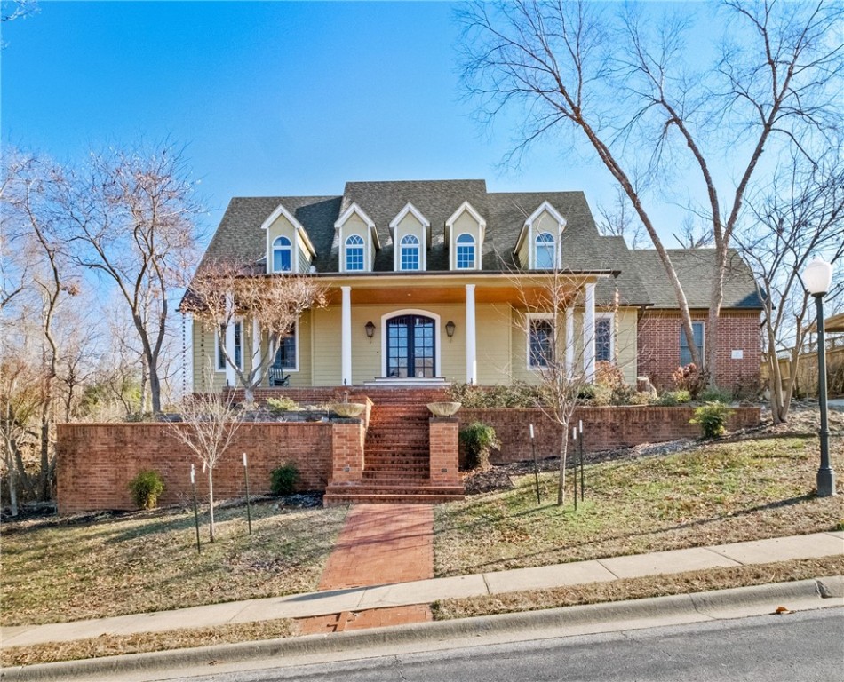 Nestled in the established sought out Hanover Neighborhood, this stunning home offers beautiful details designed for extraordinary entertaining inside & out. The front exterior features an oversized teak deck with gas lanterns that lead you into an inviting and exquisite foyer. Inside you’ll find two spacious living areas featuring a formal living room & cozy hearth room open to the eat-in kitchen. Gourmet kitchen features marble and granite counters, stainless luxury appliances, center island, large pantry & bar, complemented by a formal dining room. Enter the large primary suite through beautiful French antique doors with primary bathroom featuring double sinks, walk-in shower & jetted tub. Upstairs, a versatile bonus area and 4 additional bedrooms suites await. The backyard is an entertainer’s dream, featuring a covered patio overlooking an infinity gunite pool with waterfall edge & pergola with fireplace. Fantastic location, just minutes from downtown Bentonville & biking/mountain biking trails.