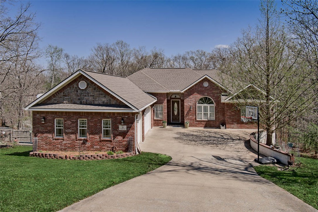 This quality constructed custom home, built by one of NWA's finest, has so much to offer & so many possibilities. On a lovely cul-de-sac, 2 minutes from golf course, pool, tennis, parks, trails. Private views of nature. 12 ft. soaring ceilings, huge windows w/lots of natural light. 2 living areas, one upstairs and one down, each with their own entrances, patios, kitchen, dining, living room, primary bedroom and primary bath. Gorgeous hardwood flooring throughout. Main floor consists of large open living room, eat in kitchen, formal DR, 4 bedrooms, 3 full baths, and utility room. Off of the second living quarters downstairs is a huge dreamy workshop/studio with double doors to the outside, perfect for at home business along with an additional spacious game room. You have to see to believe the massive storage space and available options. Very little yard work but lots of curb appeal with flower beds and garden space. Brand new top of the line H&A unit with smart home Nest system and high end air filtering system.