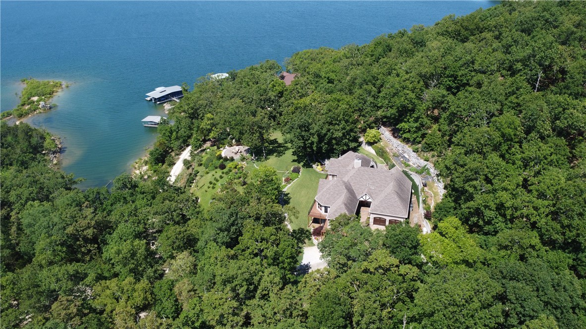 Experience Unmatched Luxury in This Breathtaking Lakefront Home on Beaver Lake!  Offering panoramic views from nearly every room.  The expansive gourmet kitchen seamlessly connects to an inviting living area and elegant dining space, perfect for entertaining.  Cozy up by one of the two fireplaces or enjoy a movie night in the state-of-the-art theater room, complete with seating and equipment.  Stay fit in the dedicated exercise room or entertain guests in the family room with wet bar.  Adorned with reclaimed wood beams and stunning Brazilian Koa floors throughout.  Includes a whole-house generator, a safe room, and much more.  Over 3 acres of impeccably landscaped grounds, featuring a golf course lawn and lush landscaping that rivals botanical gardens!  Direct access to Beaver Lake with your own private dock.  The home boasts countless luxurious details and upgrades.  Contact your agent today for a comprehensive list of amenities and updates.  Don't miss out on owning a piece of paradise on Beaver Lake.