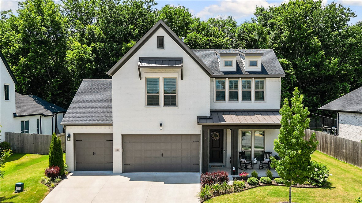 Built in 2022, this beautifully upgraded 2,360 SF home backs to peaceful trees and greenspace, offering added privacy and a serene setting. The thoughtfully designed layout features a spacious primary suite on the main with a bay window, soaking tub, glass-enclosed shower, and an oversized walk-in closet. A second main-level bedroom with French doors makes an ideal office or guest room. The kitchen offers quartz countertops, ceiling-height cabinetry, stainless-steel appliances, refrigerator, stacked oven/microwave, pull-out organizers, and a 5-burner gas cooktop. The open living and dining areas lead to a covered patio with a gas fireplace and mounted TV. Upstairs you'll find two bedrooms, a full bath, and a versatile bonus room. Washer, dryer, tankless water heater, dual-zone HVAC, and a 3-car garage are included. Minutes from trails, parks, schools, shopping, I-49, and the University of Arkansas.