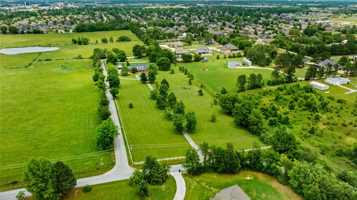 Just a few minutes from Uptown Rogers, Mt Hebron Park, the AMP and bike trails, this 7.11 acre picturesque charming property offers the perfect blend of privacy and convenience-ideal for horse or land lovers!  A long, tree-lined driveway leads to a charming brick home with 4 bedrooms, office, formal dining, hardwood floors, gas cooktop, and double gas convection ovens. Enjoy peaceful mornings on the covered porch. Property includes a 3-car attached garage, 2-car detached garage, 3-sided shed, and a classic red pole barn—perfect for equipment, storage, or animals. White split rail fencing and incredible curb appeal make this a standout. Room to roam, raise animals, or simply enjoy the privacy and beauty of your own in-town retreat! BRAND NEW Interior Paint Thruout, and All Hardwood Floors just Refinished.  New roof, hvac, water heater in 2020.