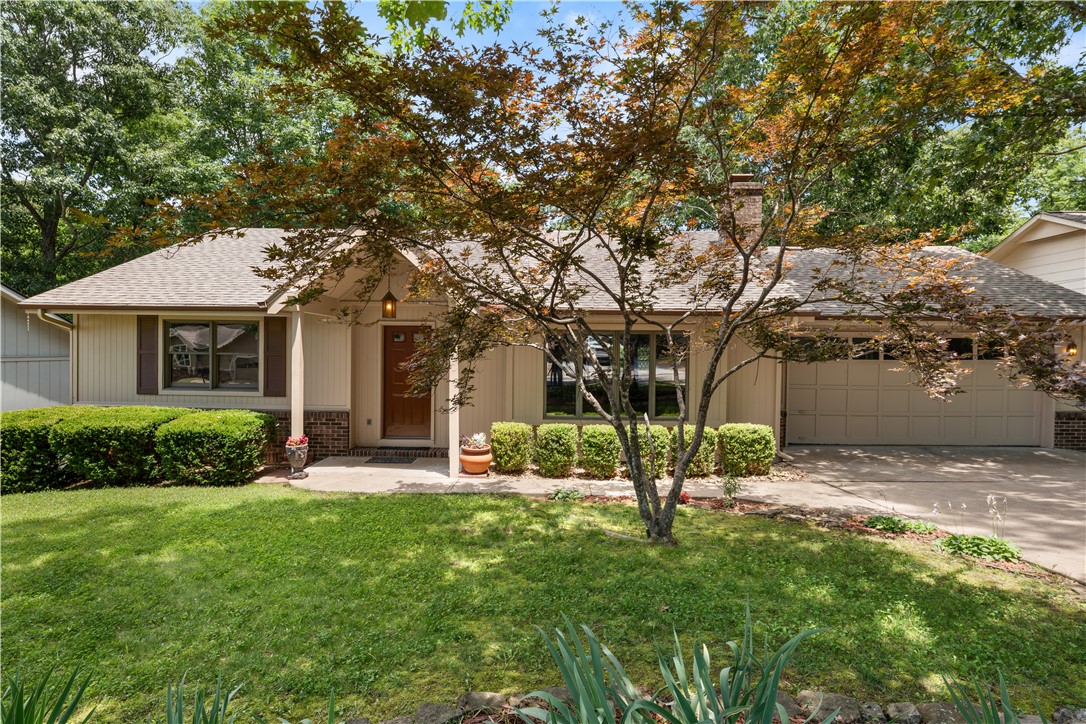 Nestled among mature trees on a beautifully landscaped lot, this move-in-ready Bella Vista home offers privacy, comfort, and exceptional outdoor living.

Recent updates include a newer roof (2023), new Masonite siding, fresh paint throughout the home, garage, and workshop, new bedroom carpet, and new flooring in the sunroom. The spacious living room features engineered wood flooring, custom built-ins, and a charming brick fireplace, while large windows fill the home with natural light.

Enjoy peaceful tree views from the bright three-season sunroom or relax on the deck overlooking the private backyard. The kitchen offers solid wood cabinetry, a pantry, and an adjoining dining area. A separate workshop behind the garage provides additional space for hobbies, storage, or projects.

Conveniently located near Bella Vista's parks, lakes, golf courses, walking and biking trails, and POA amenities, this well-maintained home combines quality updates, functional living spaces, and a beautiful natural setting.