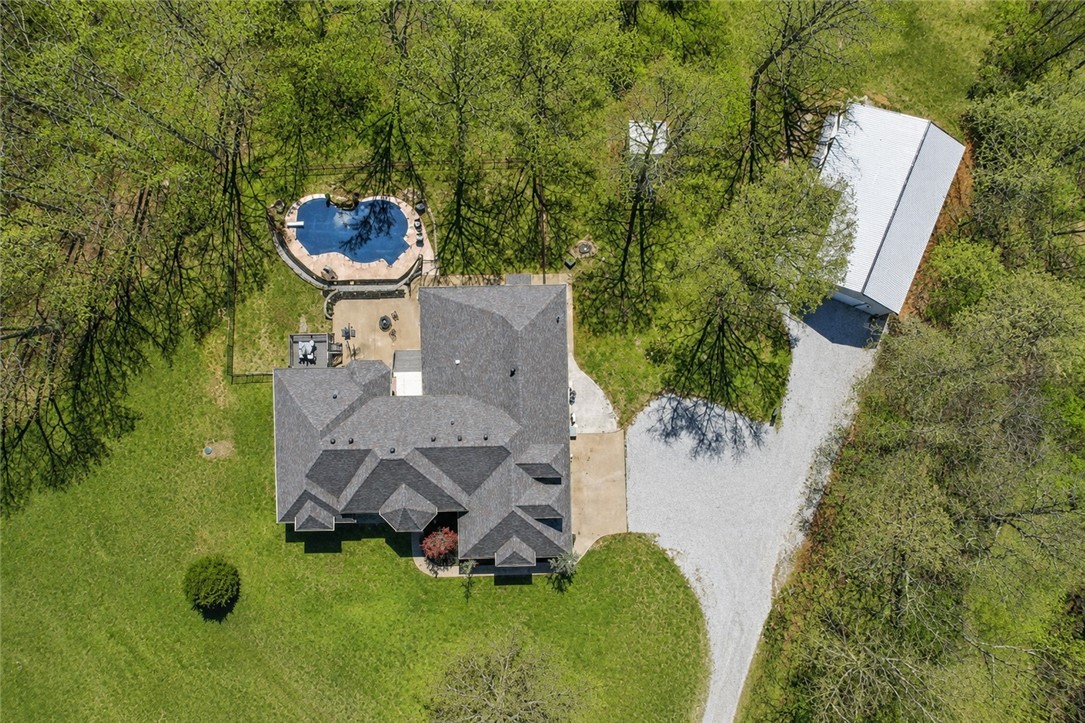 Luxury living meets privacy and versatility on 7.6 acres just minutes from Bentonville. This exceptional property offers 5 bedrooms, an office, multiple living spaces, and private baths for each main-level bedroom. The primary suite features a sitting area, dual-sided fireplace, and spa-inspired bath. Designed for both entertaining and everyday living, the home includes a spacious kitchen with granite countertops, a bright sunroom, and seamless access to the resort-style backyard featuring an in-ground saltwater pool with waterfall and expansive deck.
A newly built 30x40 shop includes an approximately 600 sq ft private ADU complete with a kitchen, living area, bedroom, bathroom, and laundry ideal for guests, multigenerational living, or a private retreat.
Recent updates include interior paint, flooring, lighting, HVAC systems, and a new roof. A rare opportunity to own a luxury estate offering acreage, a pool, shop, and separate living quarters