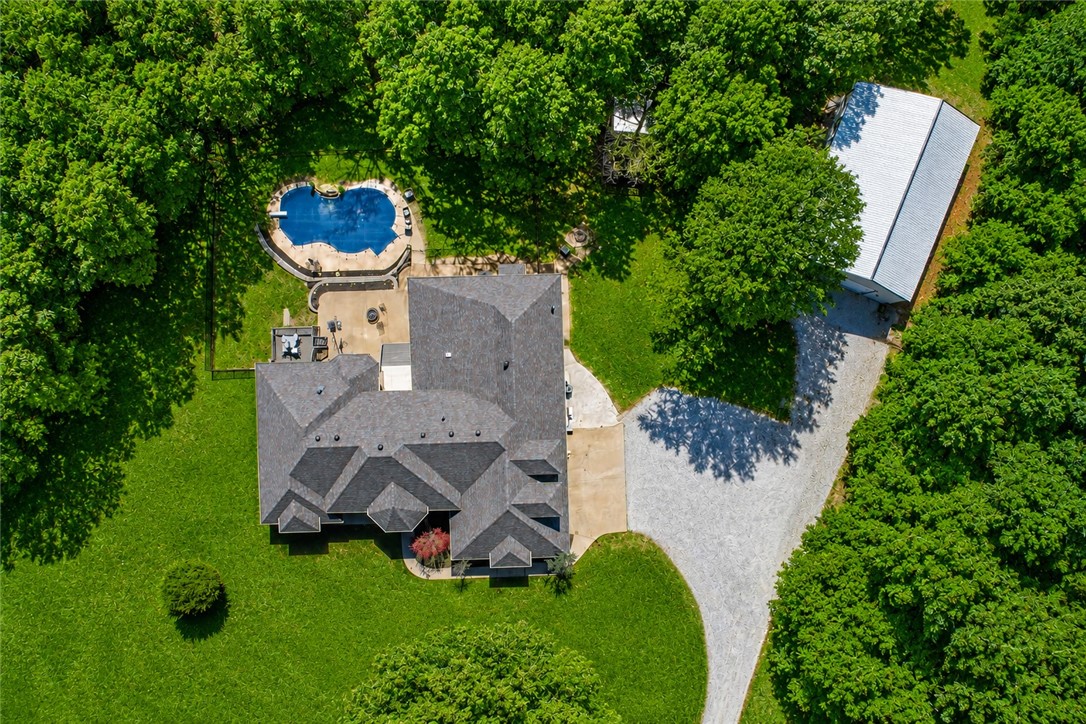 Luxury living meets privacy and versatility on 7.6 acres just minutes from Bentonville. This exceptional property offers 5 bedrooms, an office, multiple living spaces, and private baths for each main-level bedroom. The primary suite features a sitting area, dual-sided fireplace, and spa-inspired bath. Designed for both entertaining and everyday living, the home includes a spacious kitchen with granite countertops, a bright sunroom, and seamless access to the resort-style backyard featuring an in-ground saltwater pool with waterfall and expansive deck.
A newly built 30x40 shop includes an approximately 600 sq ft private ADU complete with a kitchen, living area, bedroom, bathroom, and laundry ideal for guests, multigenerational living, or a private retreat.
Recent updates include interior paint, flooring, lighting, HVAC systems, and a new roof. A rare opportunity to own a luxury estate offering acreage, a pool, shop, and separate living quarters