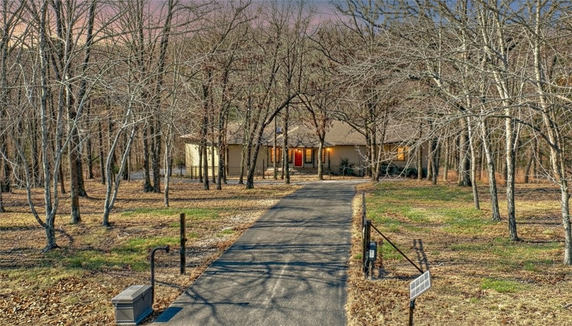 Private setting on 2.22 ac. Minutes to Beaver Lake, Short drive to downtown Rogers, Huge deck for morning coffee & entertaining. Plenty of room for pets to play. Well-built home: 2x6 framed walls for better insulation, poured concrete basement walls, & Anderson windows! F/P mantle from Monte Ne Hotel. Main level is a split plan boasting a guest bedroom w/ private bath & a huge primary bedroom with a large room just off primary for office/workout space. large walk-in closet & primary bathroom that has large tub and separate shower. Lower level offers walk out patio, open game room with wet bar/kitchenette, 3rd bedroom, full bath. Basement has two different garages that heated/cooled. One oversized 1-car &  other garage is an oversized 2-car w/ shop area & work room. Garages have 18x8 overhead doors dimensions 2020 upgrades include new paint & carpet throughout & new upstairs HVAC system. New Roof. Gated driveway for security & paved drive around the entire home for plenty of parking & RV septic connection/ cleanout.