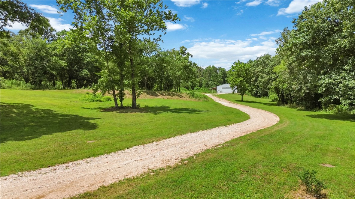 Escape to your own private Ozark retreat! Nestled on 6.12 wooded acres, this unique barndominium offers approximately 700 SF of comfortable living space featuring an open-concept kitchen and living area, one bedroom, plus a versatile bunk room with closet that also makes a great office. The attached 932 SF heated and cooled shop is perfect for hobbies, storage, or a home business with built-in workbenches and abundant workspace. Enjoy peaceful country living with a year-round creek running the length of the property, two ponds, mature woods, and abundant deer and turkey. Relax on the covered porch or explore nearby Devil's Den State Park, just minutes away. OzarksGo fiber internet keeps you connected. Plenty of room to build your dream home while already having living quarters and an incredible shop in place!