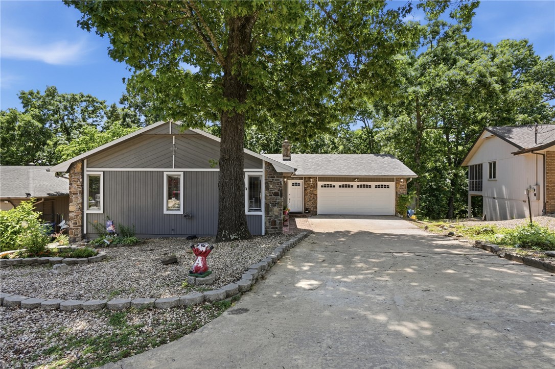 Centrally located, close to Lake Avalon, 3 bed 2 bath, 2 level home in Bella Vista. 2 Bedrooms on main floor, large main bedroom downstairs, great for privacy. Come see the extra large kitchen with cabinets galore. Huge counter space sits 7 people with large dining area as well. Perfect home for entertaining. Newer flooring. New roof & gutters 2026. Stone gas log fireplace in family room & woodburning stove downstairs. New front door, new garage door & opener , bluetooth option. Newer water heater. If you like gardening there are raised beds & the flat yard makes it fun. Screened in room off family room for 3 season enjoyment, makes a great reading area with high ceilings & great views. Outside deck with propane line for BBQ.  Refrigerator, washer and dryer convey. Home sits perfectly in central BV, near restaurants, Tanyard Creek, bike trails & minutes to new bike lift.  Perfect family home for full time pleasure or a great rental. Needs some paint and minor maintenance. On sewer conversion list with Village WW.