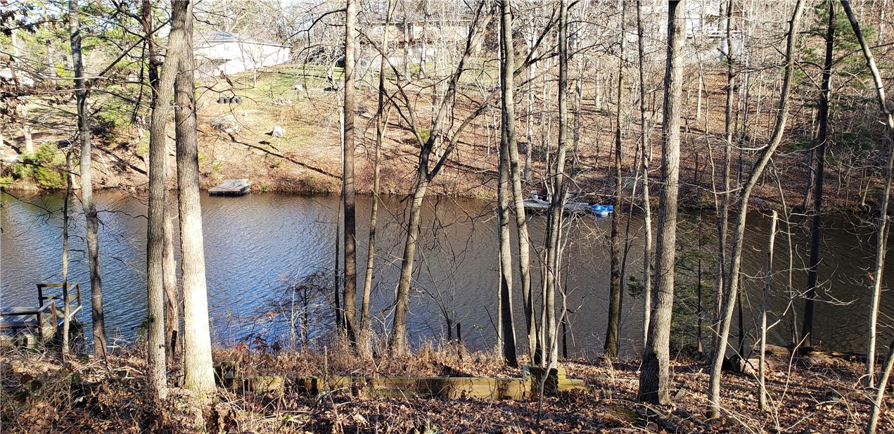 Beautiful lake front lot on Lake Rayburn – one of the most scenic and serene of the no-wake lakes in Bella Vista.  The lot is gently sloped and on a deep cove, with 70 feet of lake frontage.  Lot is very buildable and in a quiet and desirable neighborhood.  Wooden steps have already been added down to the lake and a retaining wall near the shore line to easily create a nice sitting area.  No dock currently.  Lot has been surveyed and perced.
