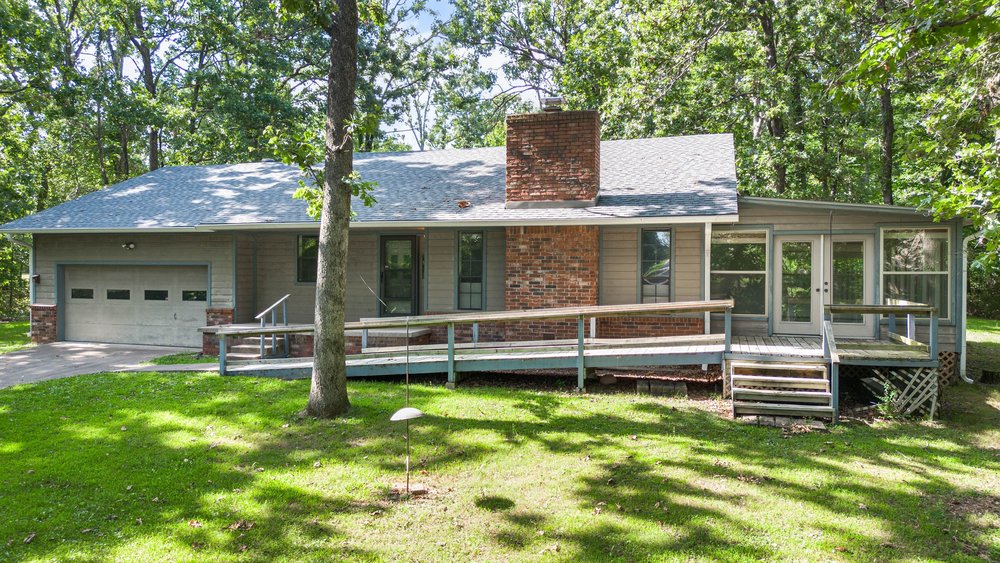 Come home to this charming house nestled in the woods on over an acre of land just outside of Siloam Springs. Enjoy the sunroom; sipping your morning coffee while watching the deer play just out the windows. The vented wood burning fireplace will keep you plenty warm all throughout the house. Enjoy the eat-in kitchen with extra pantry storage. The two extra bedrooms share an updated bathroom. The primary suite offers an exterior door to the backyard for an evening under the stars. There is plenty of storage throughout the home as well. Plus, you can store your tools in the shop out back or in the attached garage. You can fix up the guest house out back for company or maybe even an Airbnb. The property line goes to the fence line to the far right past the clearing. There is so much possibility here. Come take a look!