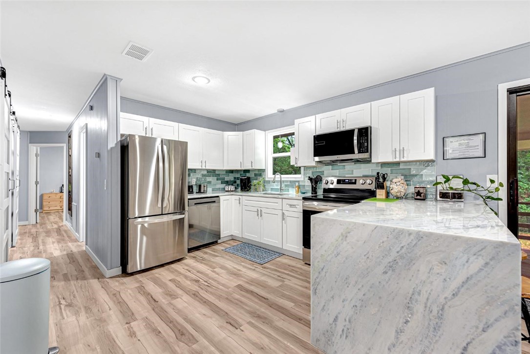 Freshly remodeled and clean as a whistle. Featuring high end finishes, a new roof and gutters Jan 2025, new heat and air units February 2026, new appliances (including refrigerator), new windows, Shadow Storm stone countertops and waterfall, waterproof LVP flooring, and a gorgeous tile shower and tub surround. This home sits on a fairly level lot and is surrounded by mature trees. The front yard is nearly all rock so very low maintenance. As a bonus this home features a 680 SQFT heated and cooled basement with potential to be your dream workshop. The basement has several outlets and plumbing in place for a sink. The Flo-Ride trail is less than 60 seconds from your front door via bike. Enjoy some of the best biking and hiking in Bella Vista without ever hopping in a car! Property is agent owned. RD eligible. Furnishings negotiable. Home is currently an AirBnB/ VRBO boasting "Guest Favorite" and "Top 10% of Listings" status at time of listing.