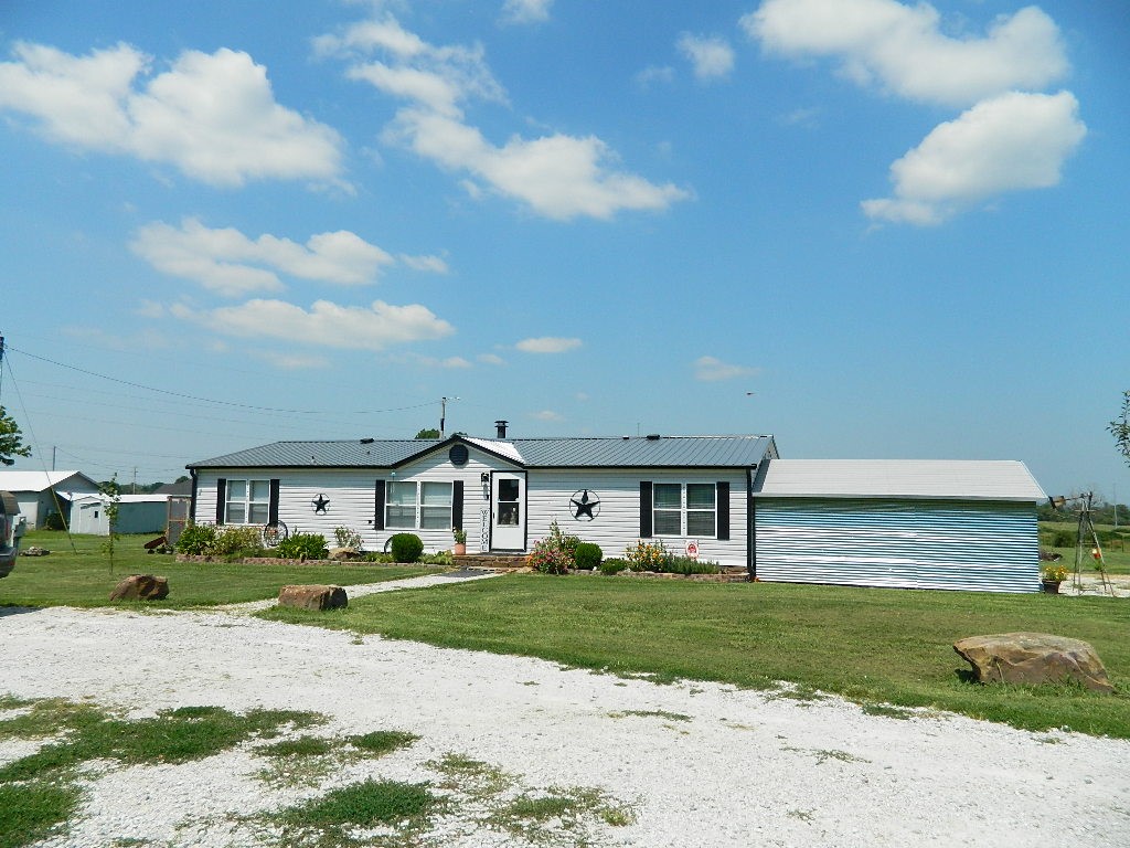 Beautiful setting on 1.7 Acres! This manufactured home has 1,568 SF - 3BR/2BA and is on a permanent foundation with native stone. The 12X12 sunroom with window unit is not included in the SF.  New HVAC, metal roof, water heater & appliances. There is also a small greenhouse and a 50-amp RV hookup. Many updates to this property. Schedule your showing today to see for yourself.