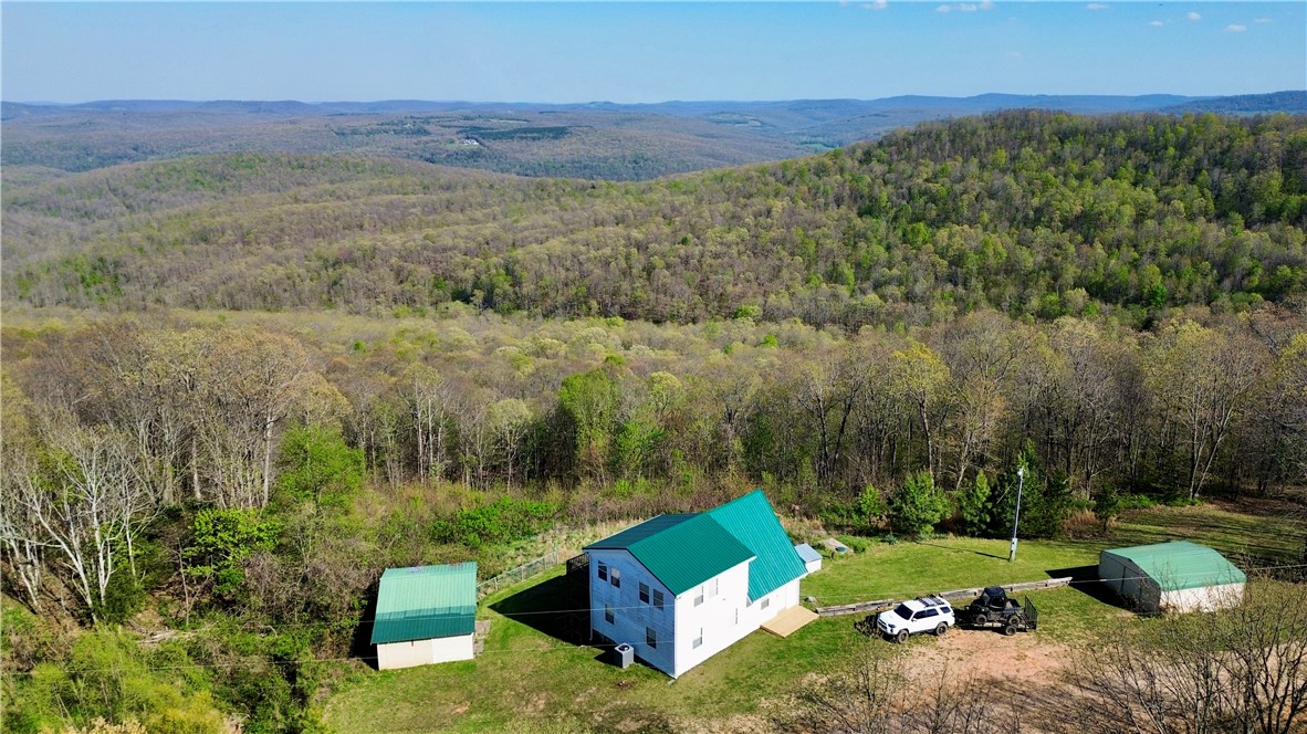 VIEWS, VIEWS, VIEWS!! Vacation calling your name? This has it all with a captivating drive to start with, gorgeous views of the Ozarks, War Eagle flowing on each side of the hwy to crossing a bridge over Seals Creek leading you to relax on your expansive deck with long beautiful views. You will not want to leave. Sold 'As-Is'. Existing well has collapsed. Fully self-sufficient, this home uses a stored water system that easily supports two occupants for over a week. Buyer to take responsibility for drilling a new well or restoring the existing water source. 3bed/2bath, all electric, 2 yr old metal roof, New Fridge. New energy eff washer/dryer. Note that the oven is currently out of order though the stove top works. 18x20 outbuilding. 20x20 storage building. The adjoining 23 acres is for sale see MLS# 1342544. Offers great hunting, hiking, camping, riding, & exploring with multiple wet weather creeks/streams traversing the property! Invest in both, escape to the Ozarks!