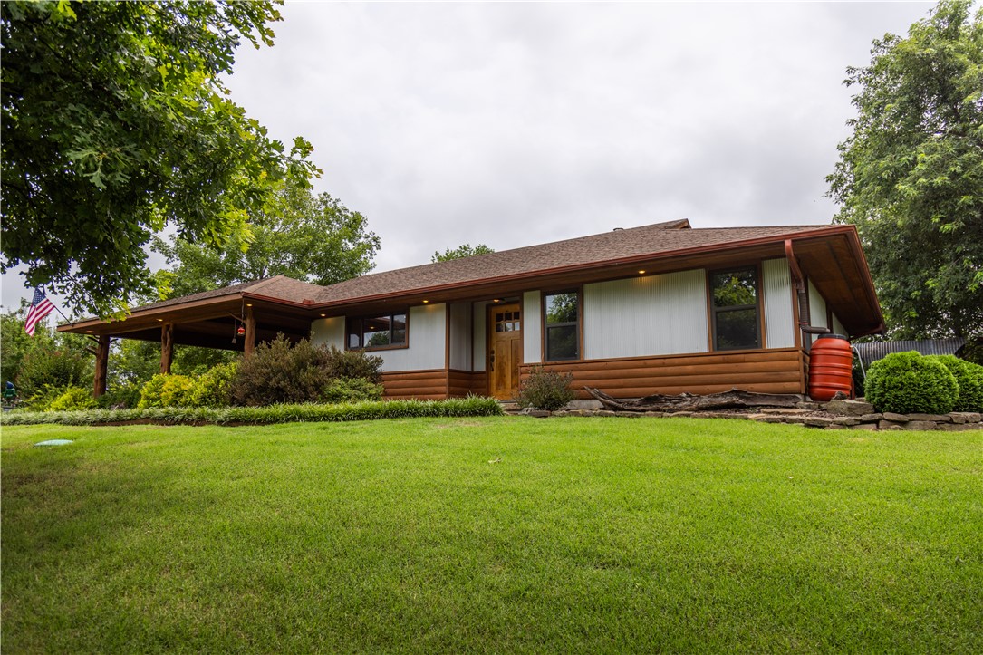 Custom-built in 2005 by Doyle Wright Construction, this exceptional 1,678 SF home sits on 10.67 acres atop a scenic bluff within West Fork city limits, offering beautiful winter views of the West Fork of the White River. Quality craftsmanship shines with custom cabinetry, solid wood doors, concrete counter tops, real cedar accents, stained concrete and tile floors, and a wood-burning stove. Enjoy a screened porch, extensive stone and vintage brick terraces, covered pavilion, and an outdoor kitchen with electricity, Mature maple trees, and a beautifully landscaped Bermuda lawn surround the home. Dramatic native stone outcroppings line the bluff, creating a breathtaking natural landscape that's perfect for exploring and enjoying the beauty of the property. 
The detached 1887 SF shop features a 14'x48' overhang, 12' roll-up door, concrete slab, heated/cooled office, storage, loft, and a well pump room. City-maintained gravel road access, privacy, and just 10 minutes to the University of Arkansas.