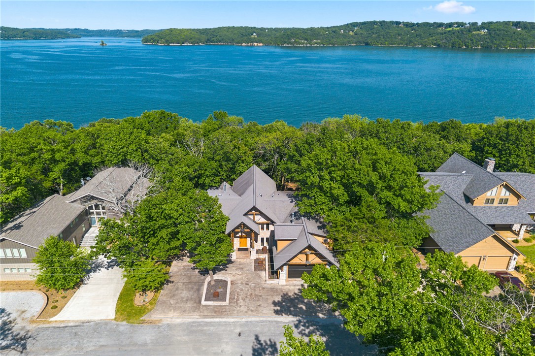 Remarkable Beaver Lake living in this custom built lake home designed for gathering, entertaining & making memories! The home thoughtfully features all 4,550 sf above grade w/4 bedrooms & 4.5 baths. The heart of the home is a majestic great room centered around a dramatic double-sided fireplace w/room to host dozens of guests! Expansive windows & indoor-outdoor flow create an inviting atmosphere ideal for lake life at its best. Kitchen includes oversized refrigerator & freezer, 2 dishwashers, 2 ovens, propane cooktop & butler’s pantry that keeps prep & serving beautifully organized. The primary suite is a peaceful retreat that occupies its own wing. While the opposite wing offers a 2nd suite, 2 bdrms & full bath, providing ample guest accommodations. Outdoor living boasts both covered & uncovered deck areas. Meander down one of the flattest paths you'll find on the north end of the lake to the home's most popular feature, a private 2-slip dock!  Community amenities nearby w/a pool, pickle ball courts, & rec center.