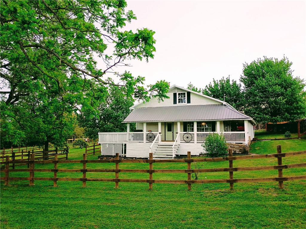 Located near the Buffalo National River, this country home sits on a productive small farm offering privacy, usable land, and modern amenities. Recently refreshed interior with a modern farmhouse aesthetic, this house stretches out with main living, kitchen, dining, laundry, mud room, 2 beds, 1 bath, and office all on the main floor with an additional bed, bath, living and bonus room all recently completed upstairs.  The property features a wraparound porch from which to view your multiple pastures with newer predator-resistant fencing, suitable for a variety of livestock. A thoughtfully landscaped surrounding and mature garden ensure plenty to enjoy outside. Three stocked ponds provide both function and recreation, including two spring-fed ponds with spring heads on site. A large barn with supplemental solar panels offers stalls, storage, and shelter.  Improvements include new AC units, electrical upgrades, hot water heaters, solar lighting, serviced septic, city water, high-speed internet and more.