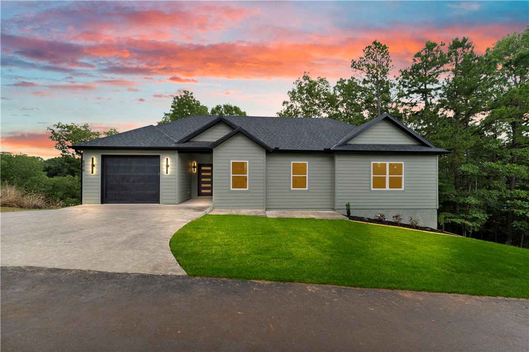 Living near Beaver Lake without sacrificing the comfort and finishes of new construction. 2026 build, this 2 bed 2 bath home offers just over 1,400 sq ft of thoughtfully designed living space on a .28 acre lot. Step inside to an open concept layout highlighted by vaulted living room, abundant natural light and a spacious living area with a fireplace, built-in cabinetry and warm wood floating shelves. The kitchen offers generous cabinetry and workspace while flowing seamlessly into the dedicated coffee bar and custom laundry room, dinning and living areas. Large sliding glass door opens to a covered back deck overlooking wooded surroundings, creating a peaceful extension of the living space. The primary suite features built-in storage and a private bath with tiled walk-in shower and modern finishes. Complete with a 1-car garage and conveniently located near Beaver Lake with access to Beaver Shores Residents boat ramp, this newly built home offers a blend of modern living and the outdoor lifestyle NWA is know for.