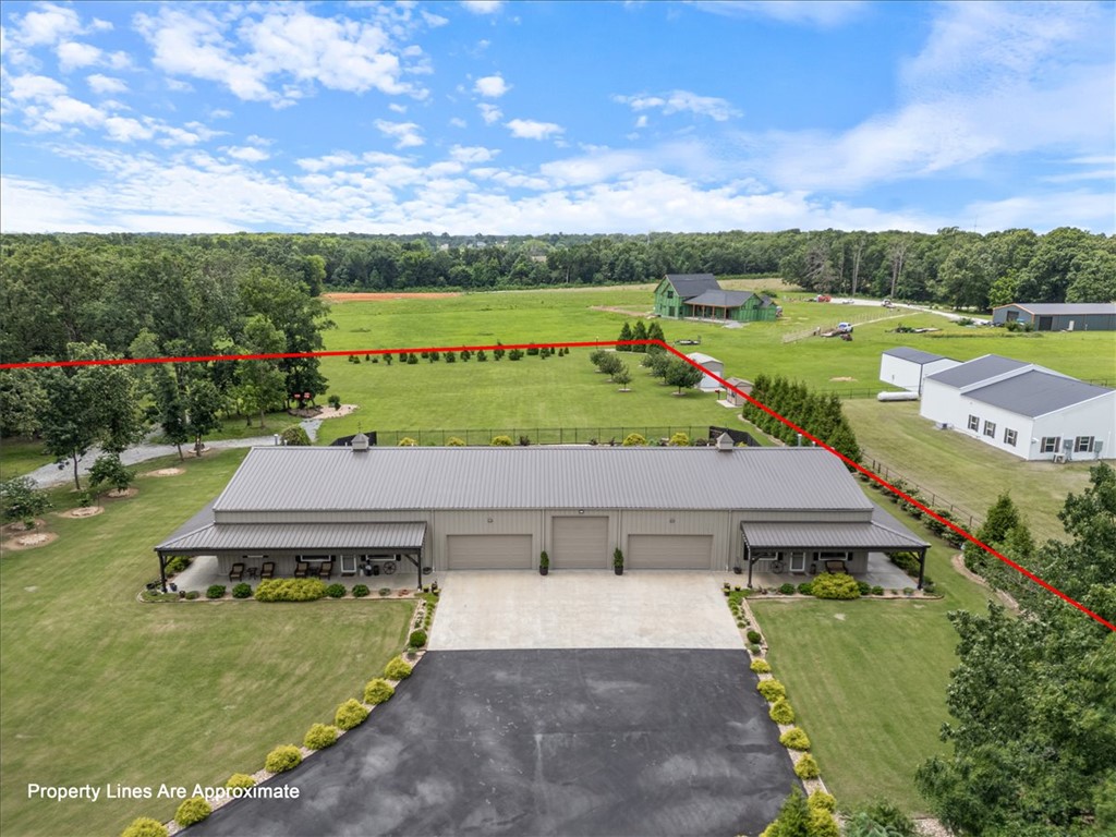 This exceptional Barndominium is built with commercial red iron framing rather than traditional pole barn or wood barn construction, offering outstanding durability and long-term quality. The property includes two separate living spaces: a 2,350 sq. ft. primary residence and a 1,406 sq. ft. ADU, making it ideal for multigenerational living, guests, or rental revenue. The home features 3 cm granite on the kitchen and bathroom countertops and windowsills, with cultured marble on all shower surfaces.  A tree-lined front road creates privacy and a peaceful setting while still being conveniently close to town, shopping, and daily amenities. With no POA restrictions, owners enjoy added flexibility. The oversized garage accommodates multiple cars and trucks, and the center bay is designed for RV parking with an in-floor sewer connection, 30-amp electric service, and water access. For added security, the siding and structure are rated for winds up to 120 mph, and an in-ground storm shelter is located in the garage area.