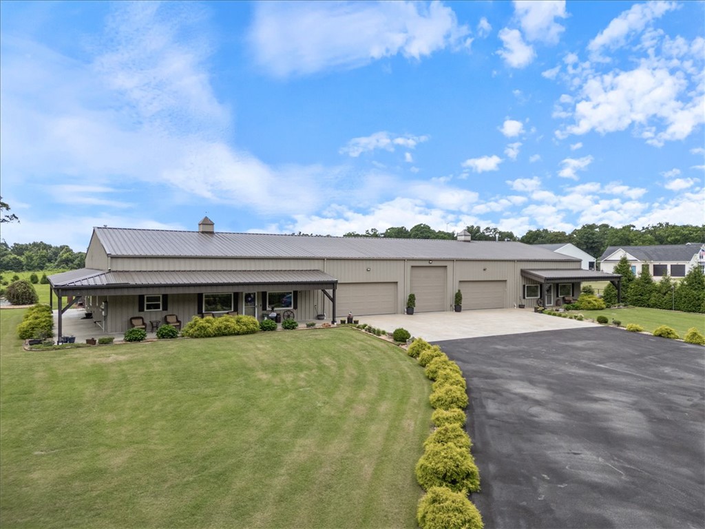 This exceptional Barndominium is built with commercial red iron framing rather than traditional pole barn or wood barn construction, offering outstanding durability and long-term quality. The property includes two separate living spaces: a 2,350 sq. ft. primary residence and a 1,406 sq. ft. ADU, making it ideal for multigenerational living, guests, or rental income. The home features 3 cm granite on the kitchen and bathroom countertops and windowsills, with cultured marble on all shower surfaces.  A tree-lined front road creates privacy and a peaceful setting while still being conveniently close to town, shopping, and daily amenities. With no POA restrictions, owners enjoy added flexibility. The oversized garage accommodates multiple cars and trucks, and the center bay is designed for RV parking with an in-floor sewer connection, 30-amp electric service, and water access. For added security, the siding and structure are rated for winds up to 120 mph, and an in-ground storm shelter is located in the garage area.