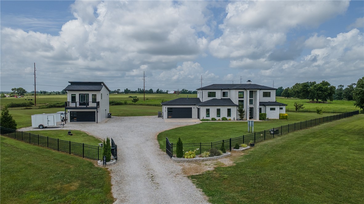 Experience the perfect blend of modern design, privacy, and versatility in this custom-built modern prairie estate, just minutes from downtown Bentonville, the new Walmart Home Office, premier dining, shopping, and world-class biking trails. Set behind a private gated entrance on 3 beautiful acres, this light-filled home features a main-level primary suite, a flexible office, wellness, or reading room, two upstairs bedrooms with ensuite baths, and a loft. The detached guest house is ideal as a mother-in-law suite, guest quarters, home office, or potential Airbnb. An oversized 3-car garage/shop offers space for a workshop, gym, storage, or recreational vehicles. Additional highlights include an underground storm shelter and zoning for Bentonville West High School and Evening Star Elementary. Modern architecture, private acreage, and income potential in one exceptional property.