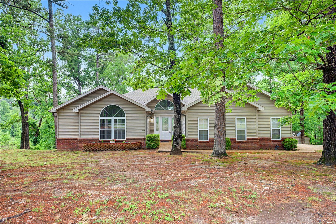 Tucked beneath a canopy of mature trees near beautiful Beaver Lake, this secluded Rogers retreat offers the perfect blend of privacy, comfort, and natural beauty. Only 20 minutes to downtown Rogers, this home welcomes you with a peaceful setting and spacious layout designed for both relaxing and entertaining.

Inside, vaulted ceilings and oversized windows fill the living spaces with natural light while showcasing the wooded surroundings. The open-concept living and dining area create an inviting atmosphere, complete with expansive glass doors leading to the back deck — the perfect place to enjoy morning coffee, entertain guests, or unwind while surrounded by nature.
The primary suite, complete with private bathroom and walk-in closet has a vaulted ceiling, large windows letting in the beauty of the surroundings and a door leading onto the back deck.  

Whether you’re looking for a full-time residence or a weekend lake getaway, this home delivers peaceful lake-area living with space, charm, and privacy.