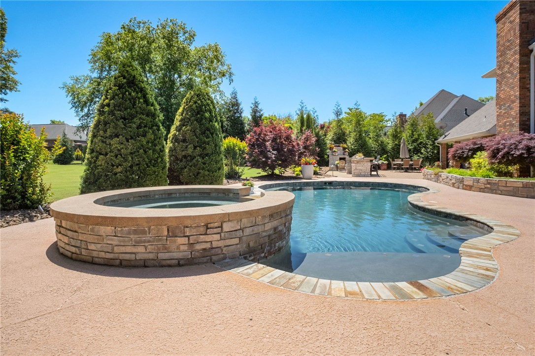 This beautifully updated residence in the prestigious gated community of Pinnacle Country Club offers an exceptional blend of timeless elegance & modern comfort. Spanning approximately 4,450 sq ft, the home features 5 bdrms, 4 full baths, & 1 half bath with thoughtfully designed living spaces ideal for both everyday living & entertaining. A dramatic great room showcases soaring cathedral ceilings & fireplace, while the gourmet kitchen is beautifully appointed w/marble countertops, double ovens, & an inviting eat-in dining area. Additional interior spaces include a formal dining room, private study, & spacious second living area offering flexibility for guests or recreation space. Situated on a beautifully landscaped 0.60-acre lot, the outdoor living experience is equally impressive with a sparkling pool & spa, outdoor kitchen, & fireplace designed for year-round enjoyment. Completing the property is a desirable side-entry 3-car garage, all within one of Northwest Arkansas’ most sought-after golf course communities.