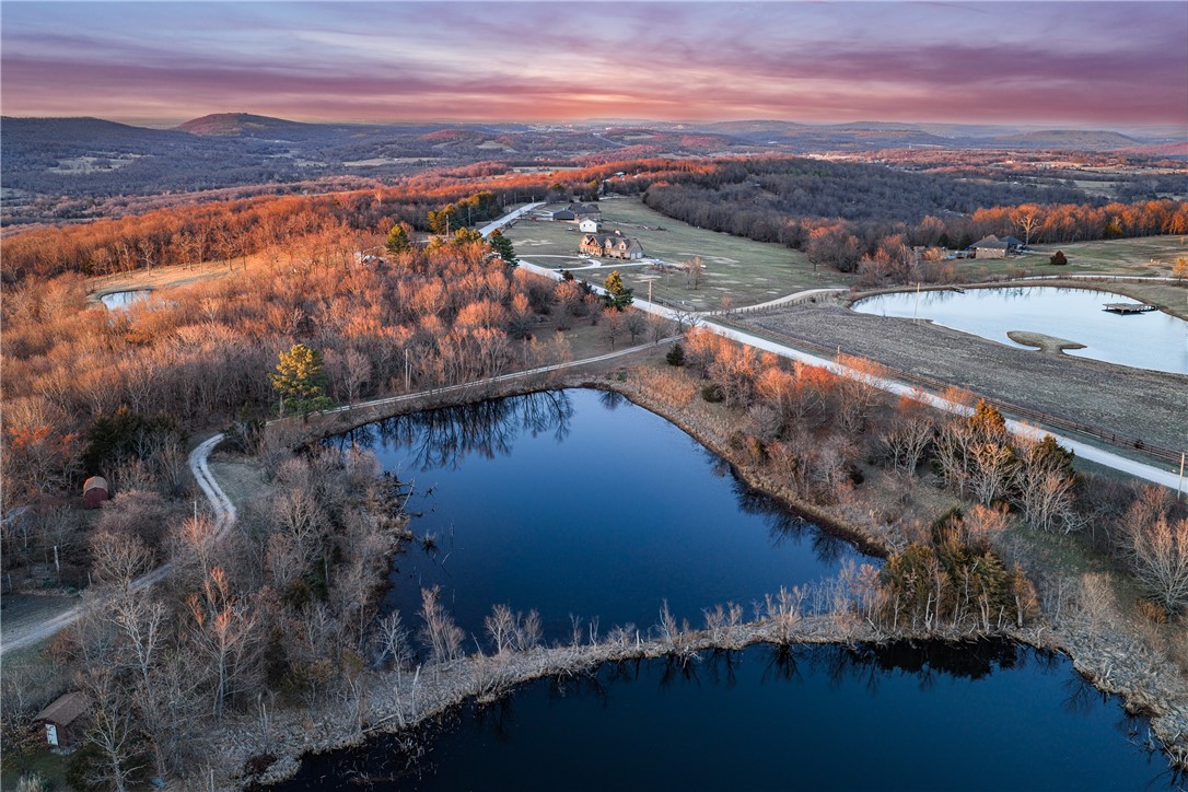 This Charming 3 BR 2 Ba ranch-type home was custom built and nestled on this 24 acres on Tony Mountain just South of Fayetteville.  The Home boasts an open Living area with wood burning fireplace, vaulted ceiling, and built-ins, Bright and cheery kitchen with granite countertops and a great view of the lake. The Sunsets from the back side of the home are spectacular as well! Split Bedroom plan. The Primary Suite is spacious with view of the Lake and a see-thru fireplace into the primary bath with jetted tub. There is a central Vacuum, Granite Countertops, tile floors, Berber carpets. Roof is approximately 7 years old. Screened covered porch overlooking the private lake.  Large 2 car garage with closets and above the garage is a finished studio room with wall a/c.  Welcome Home!