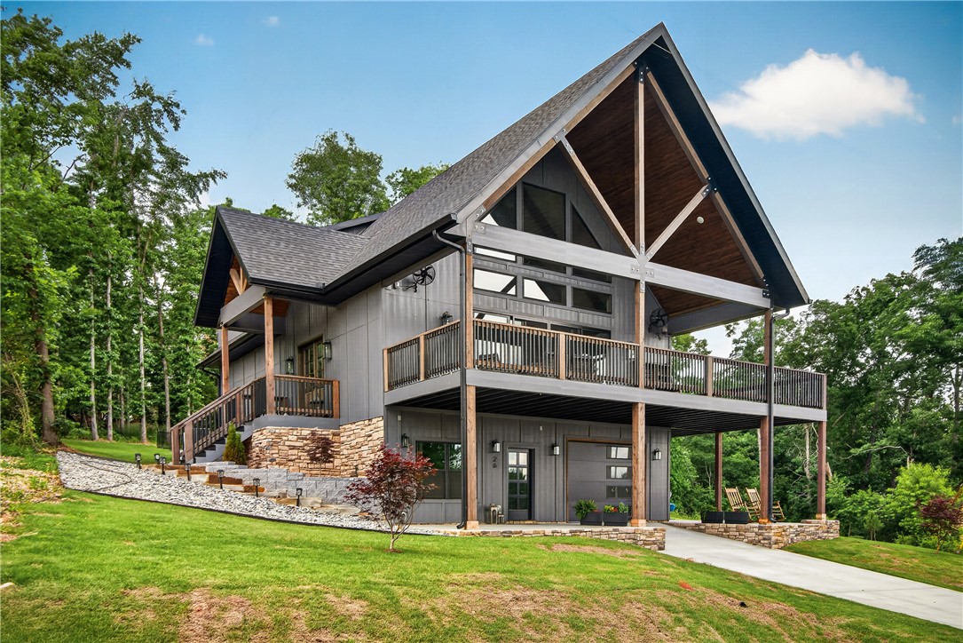A stunning lake-view home built in 2025 overlooking Lake Loch Lomond and Lakepoint Marina. This 3-bedroom, 2 full bath, 2 half bath home features soaring 25-foot ceilings, expansive windows, and an open-concept design that maximizes natural light and water views. The kitchen boasts quartz countertops, a stone backsplash, abundant cabinetry, a large island, and a built-in wireless pop-up charging station. The spacious primary suite includes private deck access, and the laundry room conveniently connects to the primary closet. A separate entrance leads to a dedicated office/flex space, ideal for working from home or hosting guests. Enjoy outdoor living on the oversized front deck engineered to support up to 90 people, plus a private rear deck off the primary suite. The tandem garage provides additional storage space. Modern finishes, functional design, and exceptional lake views make this one-of-a-kind property a rare Bella Vista opportunity.