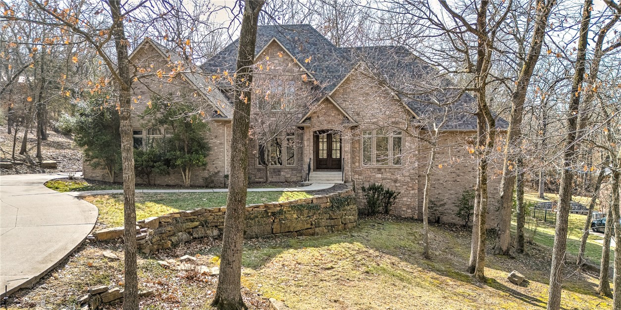 Luxurious home located in one of the most desirable neighborhoods in Fayetteville--just minutes to the Razorback Stadium, Bud Walton Arena and all that the University of Arkansas has to offer! This beautifully designed home with high end finishes has a feeling of being warm & cozy with all the natural light from the gorgeous windows throughout the house and lovely woodwork. The interior features an open floor plan, hardwood floors, custom cabinets, kitchen island, formal dining, designated office, plantation shutters and spacious walk-in closets throughout--just to name a few. The exterior was meticulously planned out with the screened-in back porch, wired with sound to enjoy the breathtaking view of the 1.09 acre wooded yard. The front lawn is professionally manicured with shrubbery, mature trees, a retaining wall, and a circular driveway. No other neighborhood offers similar peace, quiet and privacy while being so close to the excitement of Fayetteville!