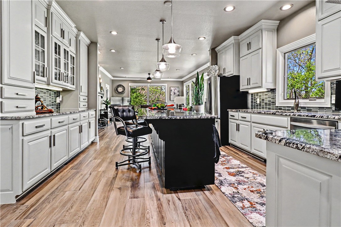 Quality-built with timeless OAK construction and a recently updated interior, this home blends craftsmanship with modern comfort. The open kitchen features a large island, pantry, and oversized appliance cabinet, flowing seamlessly into the hearth room with floor-to-ceiling windows for abundant natural light. Ideal for entertaining, enjoy a formal dining room and spacious living area, plus a private office just off the kitchen. The large primary suite offers a tray ceiling with rope lighting, and a bath with double sinks, vanity area, and a walk-in tower shower. A half bath and laundry are conveniently located nearby. The lower level includes spacious bedrooms, a great room with patio access, and a hobby room with exterior doors. Relax on the updated composite deck. Conveniently located near I-49, trails, golf, tennis, and pools. See attached amenities and updates list.
