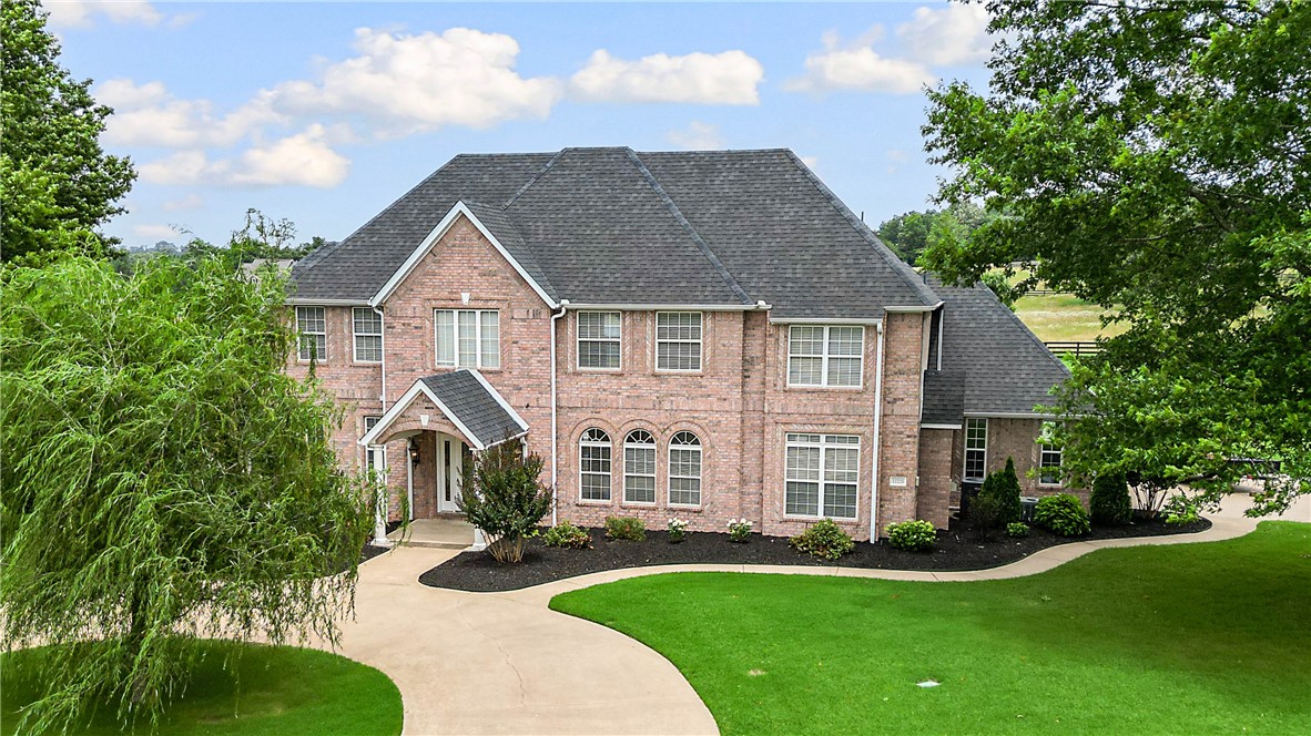 Rare opportunity to own a stunning home in one of Northwest Arkansas's premier gated communities. Situated on three picturesque acres, this exceptional property blends timeless elegance with an open-concept design. Expansive picture windows showcase beautiful natural views, while the chef's kitchen flows into a vaulted family room with two sets of French doors leading to a 1,000-square-foot covered patio. The main-level primary suite offers private patio access. Upstairs features four spacious bedrooms plus flexible space for a game room, media room, or fitness area. The main level also includes a formal dining room with seating for 12, a private office or den, and two gas fireplaces. Recent updates include a 2020 roof, newer appliances, and LeafFiter gutter guards. Enjoy the privacy and tranquility of country living with the convenience of shopping, dining, schools, and all the amenities of Northwest Arkansas just minutes away.