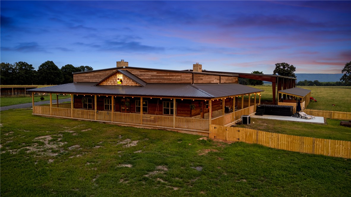 Nestled in the heart of 115 breathtaking acres, this rare country retreat offers unmatched privacy, serenity, and room to live the lifestyle you’ve been dreaming of. The home enjoys sweeping views of Petit Jean Mountain in the distance, creating a picture-perfect backdrop from every angle. Fenced and cross-fenced, ideal for livestock, horses, and family pets, and includes two scenic ponds that enhance both beauty and functionality. A covered wrap-around porch invites you to sit back, relax, and take in the sights and sounds of peaceful country living. Equestrians and hobby ranchers will appreciate the large horse arena attached to the back of the home, complete with a stable and an adjoining bar/entertaining area, making it the perfect place to gather after a long day on the farm. Whether you're seeking a working ranch, a private homestead, or a weekend escape, this property delivers endless possibilities with views, space, and features you simply won’t find anywhere else.