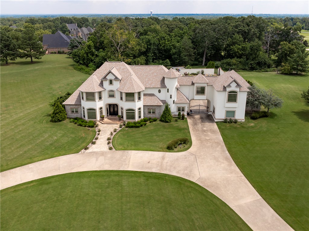 Welcome to 11220 Talamore, centrally located in Bentonville’s most coveted neighborhoods. The modern French Normandy exterior design features stucco, brick, stonework, striking pitched rooflines, and a stately presence that exudes an elegant, storybook luxury. 
This European styled property is on 4.11 acres surrounded by mature landscaping and  features an exclusive, completely walled-in secret garden sanctuary that offers a tranquil escape designed for ultimate relaxation with a sparkling salt-water pool perfect for cooling off on warm Arkansas afternoons or hosting intimate evening gatherings. 
Custom Fleur-de-lis Wrought Iron doors open to the foyer entry with a curved staircase & French doors open to the dedicated library office. Enjoy the bright interiors that boast expansive, light-filled living spaces,  millwork throughout, high-end chef's kitchen, & an expansive main level primary suite that serves as a private retreat.
This remarkable estate provides a backdrop for grand lifestyle living; Welcome Home!