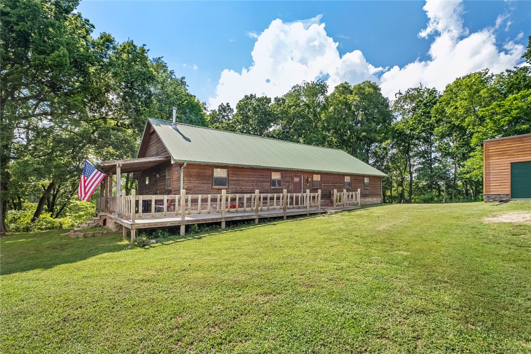 Beautiful cabin living on 5 acres +/- in country setting not far from town! This home features a rustic charm starting when you walk through the door! Chef's kitchen with dark stained wood cabinets, granite countertops, island with step up bar seating, open concept to the living room that features  stone hearth that extends to ceiling behind the freestanding wood stove. Cathedral ceilings in living room opening into the loft area (currently used as home office space) that looks over living & kitchen. Upstairs features bedroom #3 closed off from loft area. Downstairs includes main and 2nd bedrooms along with en-suite main bathroom with custom features of built-in soaking tub, walk-in shower with rock surround, and large walk-in closet. Detached 30x60 shop includes two garage doors, insulated walls w/osb, and plenty of space for projects or storage! New well pump. 6 minute drive to downtown Pea Ridge.