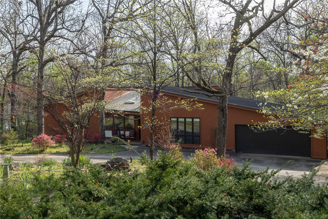 Stunning mid-Fayetteville contemporary home built by David Rose. Located in the secluded Rosewood Addition of Rolling Hills, this 1-level home features 3 full bedroom en suites. The remodeled kitchen has beautiful granite countertops, stainless jenn-aire appliances, craft cabinets and opens to the living room and formal dining room. The grand living room has a sweeping wood ceiling with large skylights, native stone fireplace and opens to a lovely sunroom porch. The primary bedroom boasts a vaulted ceiling, laminate flooring and large walk in closet. A soaker tub centers the primary bathroom with walk-in shower and laundry. One of the suites is set up as a in-law quarter with plumbing setup. The cherry on top is the extraordinary lot studied with trees, landscaping, natural bird habitat. Enjoy soaking in your hot tub on the private deck. There are two flex rooms that could serve as dog rooms, studio space or extra storage. Located near trail access, walkable to grocery store and Butterfield Elementary.Pella windows