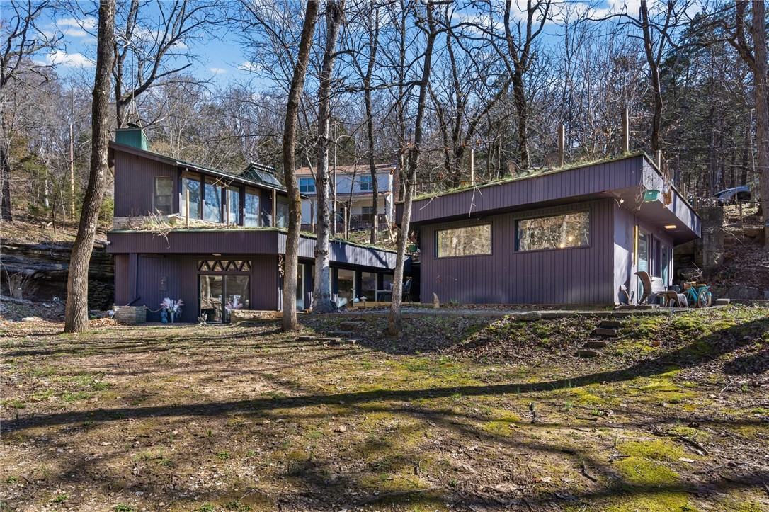 One-of-a-kind property in Lost Bridge Village, designed and built by architect Charles Willis (mentored by the legendary E. Fay Jones). Fully renovated with luxury finishes in 2024–2025 and dramatically integrated directly into a natural cave/bluff. Exposed cave walls, stacked rock accents, soaring ceilings, steel framing, and a dramatic spiral staircase create an unforgettable, organic living experience that blends architecture with the Ozark landscape. Upgraded appliances include a convection oven, plus an induction cooktop. Grass roofs add incredible character and seamless natural integration.
Enjoy usable yard space with two ponds, three decks (including a rooftop deck), an outdoor cave bar/patio, a seasonal waterfall and stream, and seasonal lake views. Multiple primary living units, parking for 7+ vehicles, and trailer space enhance the versatility.
All with full Lost Bridge Village amenities: sewer, water, pool, clubhouse, library, marina, beach, and church. A true showstopper and architectural gem