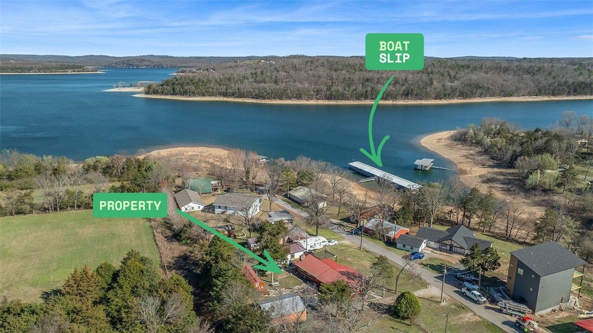 Fully Furnished Lake Resort w/a Boat Slip? Look no further! This charming 2-bedroom, 1-bath stick built cabin offers year round lake views & lots of space for entertaining w/2 living areas, large kitchen, built-in bar, & a large dining area. New HVAC & Ductwork in 2020, new windows & sliding glass doors in 2021, new carpet in 2025, & a full list of other upgrades! Outside, you’ll find awesome chainsaw art, custom flowerbeds, & even an outdoor shower! Out front you have horseshoe pits, 2 firepits, a grill, & enough seating for everyone. Next up is a 24x30 shop fully stocked w/games & water toys to keep the kids happy! In 2022, they added an additional cabin equipped w/a half bath & room to sleep 6! RV Parking w/full hookups & the 2018 26-foot Bumper pull Camper can be negotiated if the price is right, giving you additional sleeping space for guests. For boating & water lovers, the property comes w/a 9x20 boat slip in the community dock, along w/a 6500lb boat lift. The seller kept his 24ft Tritoon on there w/ease!