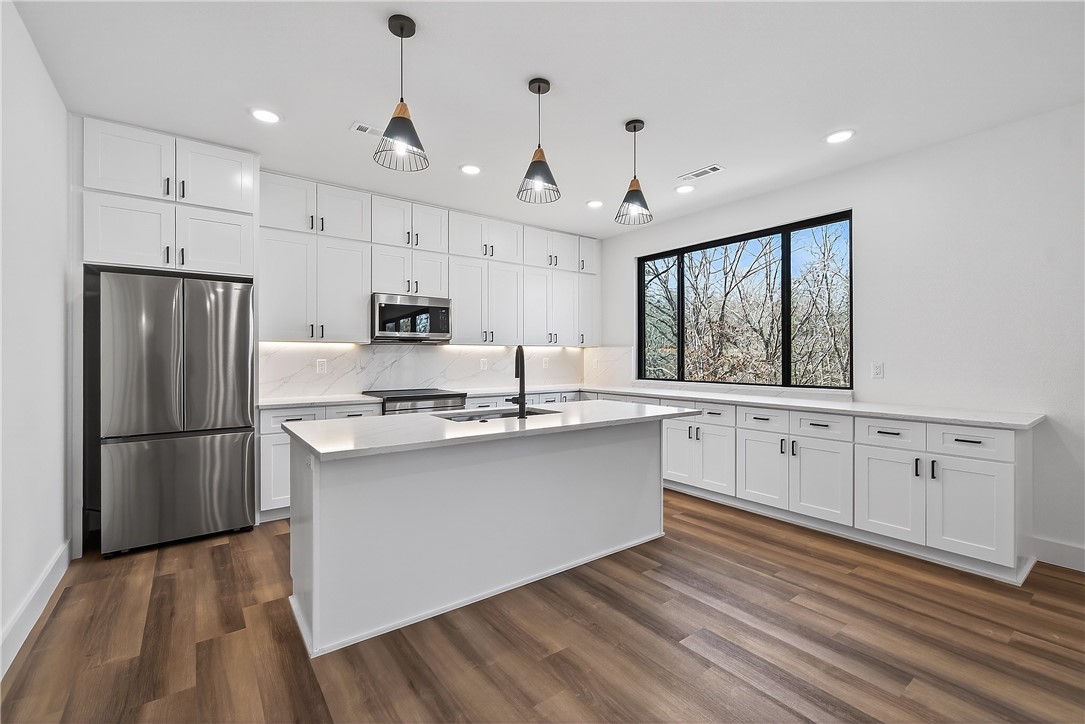 Look no further, this beautiful new construction home is perfectly situated in the heart of Bella Vista! Located in the Bentonville School District and just 15 minutes from the new Walmart Home Office, this home backs up directly to the Tunnel Vision Bike Trail, offering unmatched access to Bella Vista's renowned trail system right from your backyard. Inside, you'll find 10-foot ceilings, custom cabinetry, granite countertops, large windows, luxury vinyl plank flooring, and stylish modern finishes throughout. The open split floor plan is designed for functional everyday living, featuring a spacious primary suite and walk-in closets. The outdoor deck overlooks a wooded setting, ideal for nature lovers and those seeking privacy all while being close to daily conveniences.