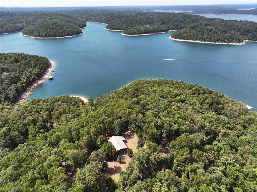 Discover Your Slice of Paradise! Welcome to a 42-acre m/l estate that seamlessly blends natural beauty with modern comfort. Experience the serene beauty of wet weather creeks, picturesque bluffs, and lush hardwood forests with your own private roads. Enjoy 1,430 ft m/l of Beaver Lake shoreline in your own private cove with your personal dock featuring 2 10x26 boat slips and large swim deck. The natural surroundings are preserved by underground electric service. The property includes a 40' X 60' building, with a 1,280 sq ft charming living quarters. There is a cozy living room, dining room, kitchen upstairs. Downstairs there is a 2B 1B.  The work area within the building provides abundant storage with large garage doors (10’x10’ & 12’x12’). Take full advantage of these amenities to enjoy lake activities and to serve as a staging area while you build your dream home at one of several panoramic view sites or near the shoreline. This rare and unique find does offer it all. Schedule your showing today!