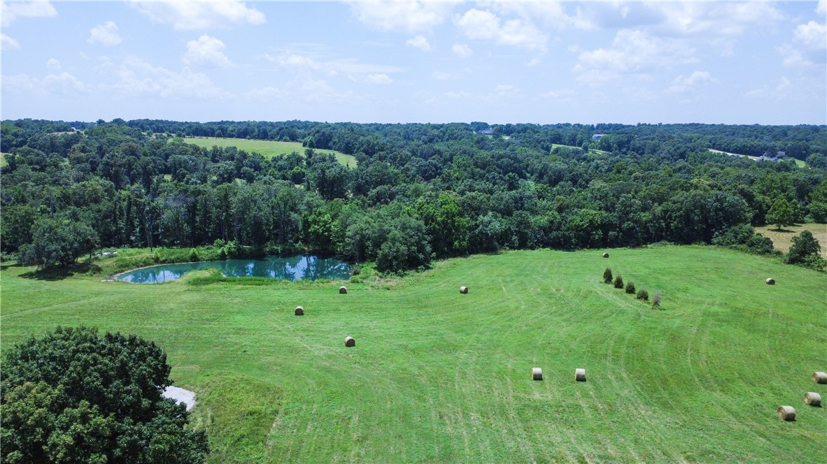Discover the perfect blend of privacy, usability, and natural beauty on this exceptional tract of land. The acreage is beautifully maintained and offers a rare combination of open space, wooded privacy, and scenic views—ideal for anyone seeking a homesite, hobby farm, recreational retreat, or investment property. A stocked 0.5-acre pond enhances the landscape and creates an inviting setting for fishing, wildlife, and relaxation. The land is laid out to support a wide range of uses, from livestock and gardening to building expansion and outdoor recreation. Supporting improvements include a 1,480-SF detached garage with three drive-in doors—perfect for equipment, vehicles, or workshop needs—and a 3,430-SF pole shed offering extensive covered storage for farm implements, trailers, or additional hobby space. The existing home complements the land with practical features such as a FamilySAFE storm shelter and a 1,786-SF covered patio overlooking a fully fenced 5,340-SF yard, ideal for pets or contained outdoor activity.