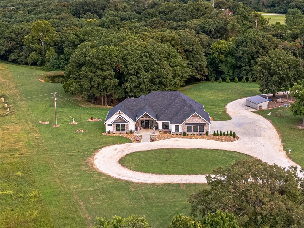 Step into the charm of this delightful 3,600 SF home with 4 cozy bedrooms nestled on 12 picturesque acres. This gem includes a spacious 3,796 SF shop with a 1,400 SF lean-to for equipment and a 1,652 SF complete apartment used as a part-time Airbnb retreat with good reviews. Embrace the farm-like allure, just a stone's throw from town. Enjoy thoughtful touches like central vacuum, spray foam insulation, a covered porch, open/covered patios, a sprinkler system, security features, indoor/outdoor wood fireplaces, and a safe storm shelter. Delight in a powered greenhouse, thriving garden, serene pond, and an outbuilding with a powered chicken coop complete with a friendly goat and ducks. Inside, find granite countertops, an oversized kitchen island, clever built-ins and blackout shades throughout. A true haven of luxury.